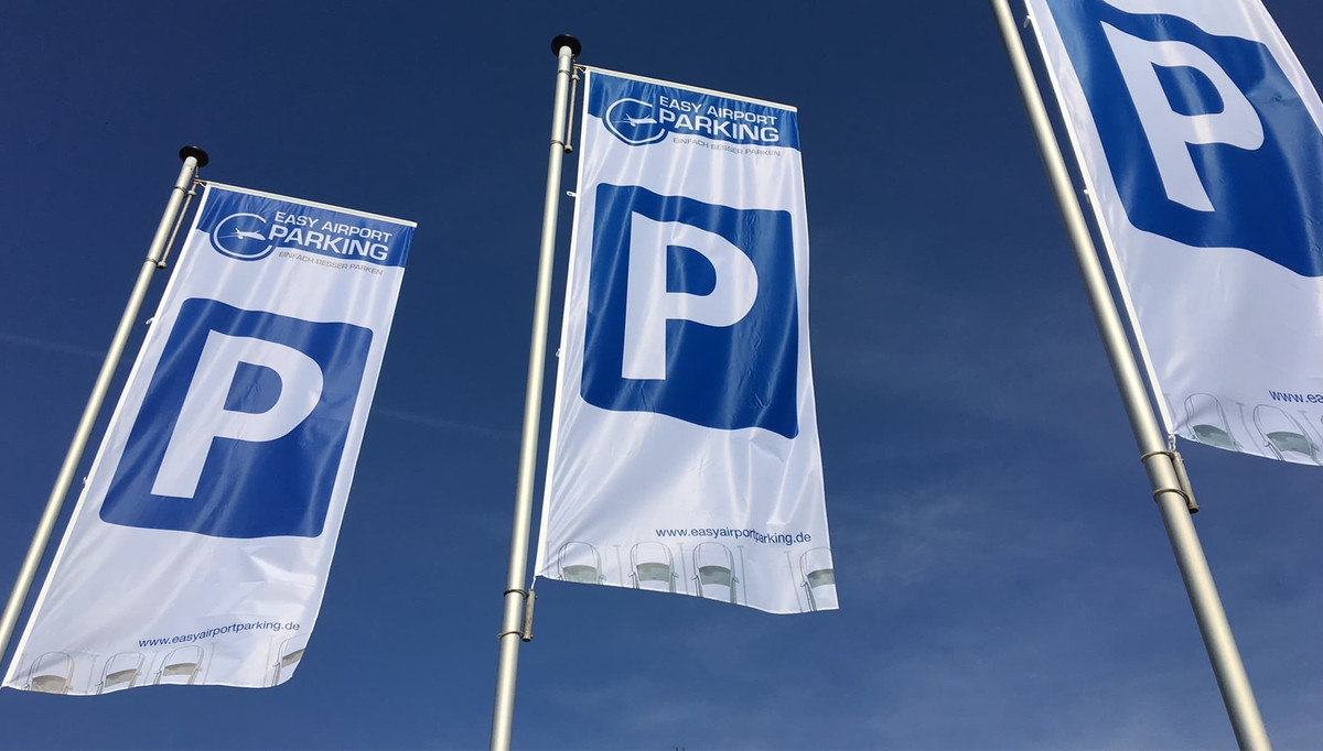 Tre flag med Easy Airport Parking-logo og parkeringssymbol på parkeringspladsen hos Easy Airport Parking ved Eindhoven Lufthavn (EIN)