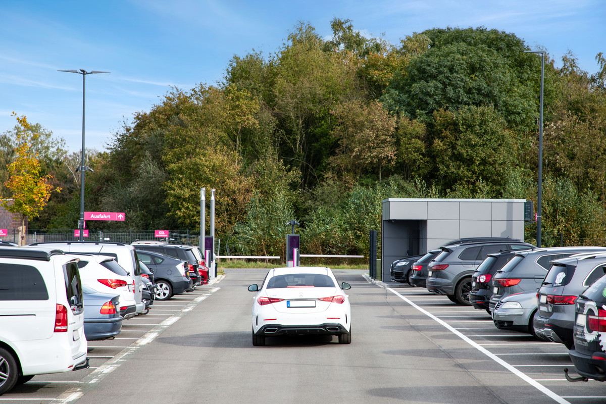 Witte auto rijdt door een brede, geasfalteerde parkeergang van de Easy Airport Parking parkeerplaats bij luchthaven Münster/Osnabrück (FMO)