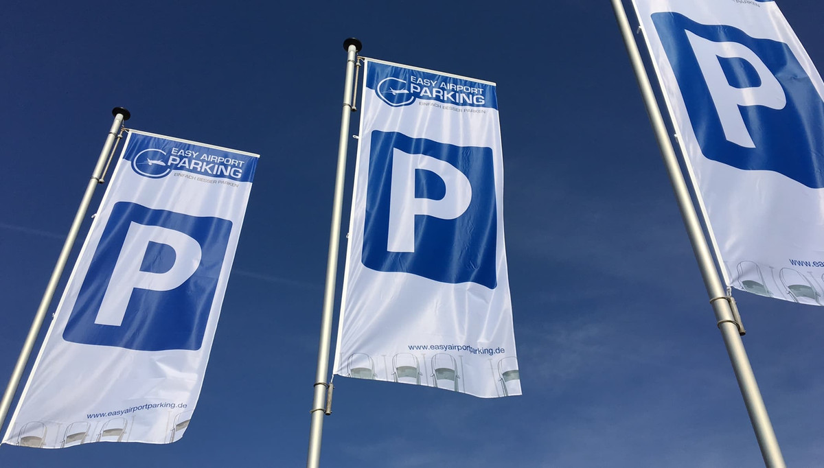 Drei Fahnen mit Easy Airport Parking Logo und Parkplatzsymbol auf dem Parkplatz von Easy Airport Parking am Flughafen Frankfurt-Hahn (HHN)