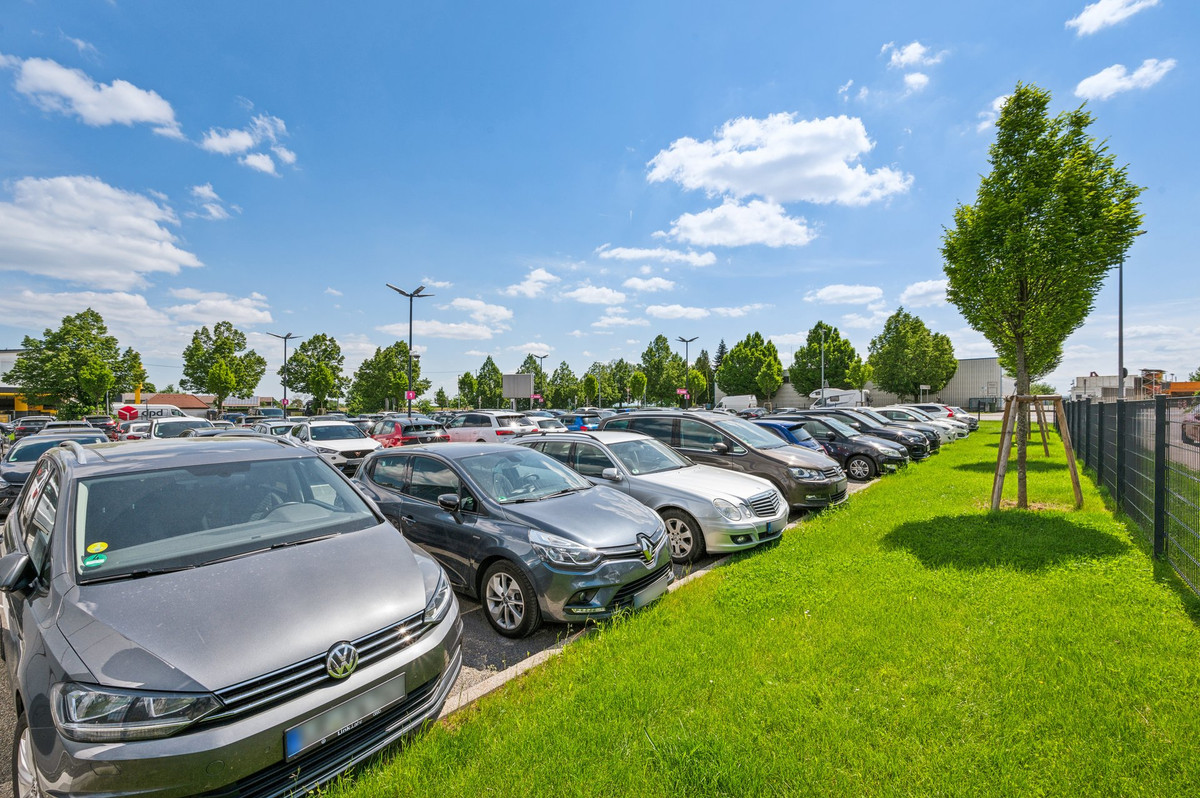 Verzorgde groenstroken aan de rand van de met auto's gevulde parkeerplaats van Easy Airport Parking op luchthaven Stuttgart (STR)