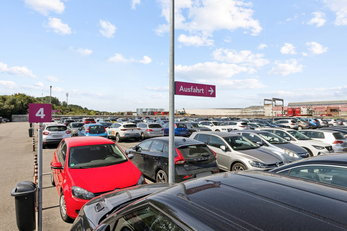 Parkerede biler og informationsskilte på Easy Airport Parking-parkeringspladsen i Weeze Lufthavn (NRN)